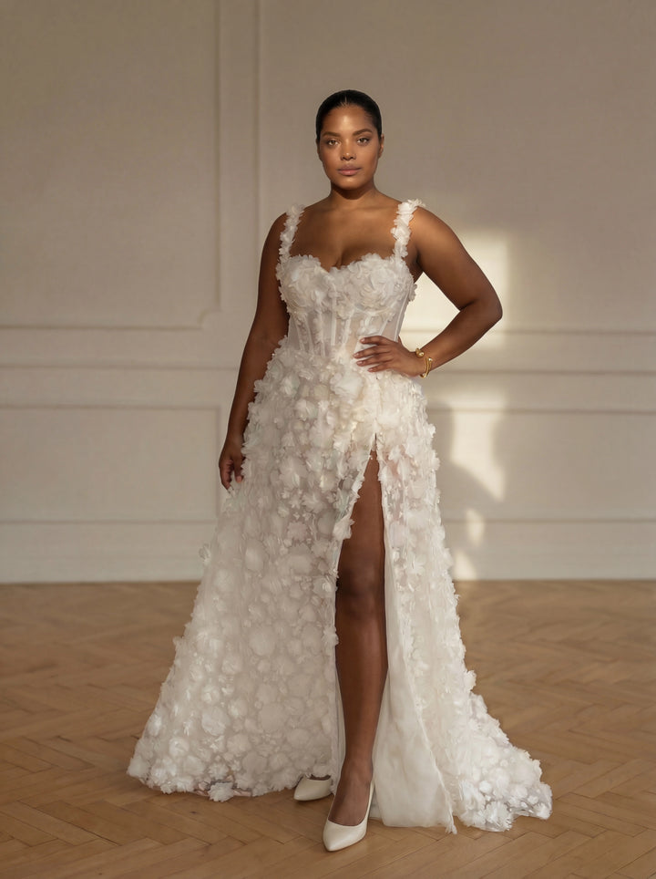 Woman wearing a white floral wedding dress with a high slit on a wooden floor.