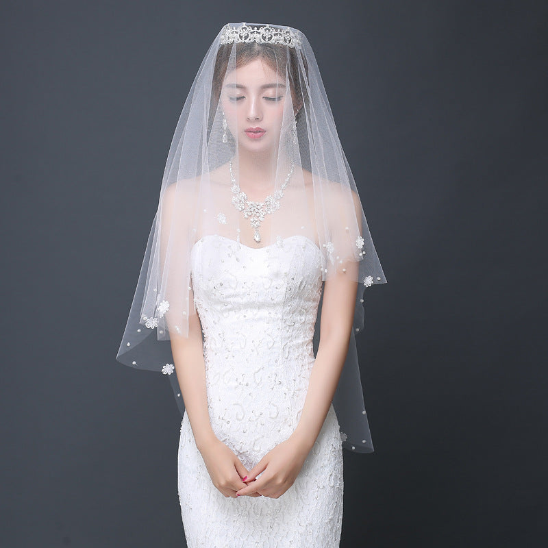 Woman wearing a white wedding dress and veil against a dark background