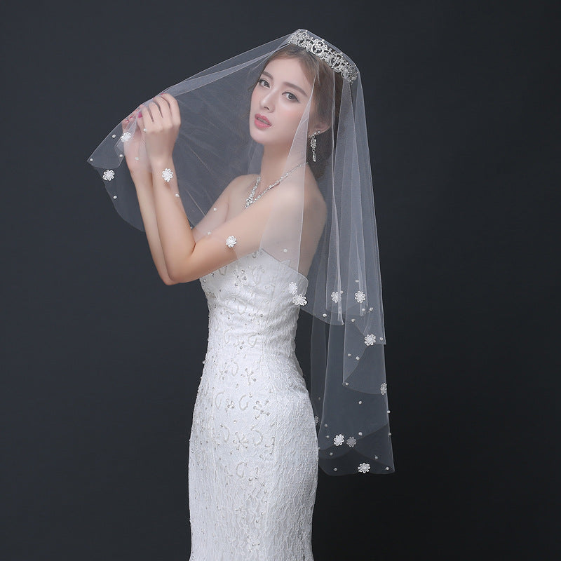 Woman in a white wedding dress with a veil against a black background