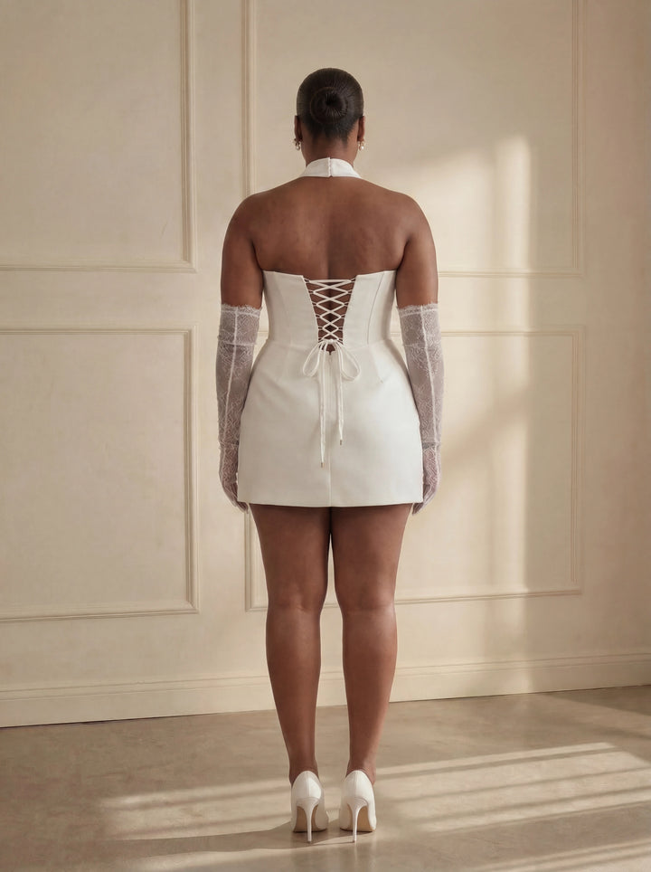 Woman wearing a white dress with sheer sleeves and lace-up back in a sunlit room.