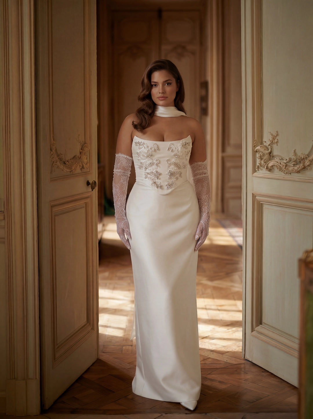 Woman in a white wedding dress standing in a doorway with soft lighting.
