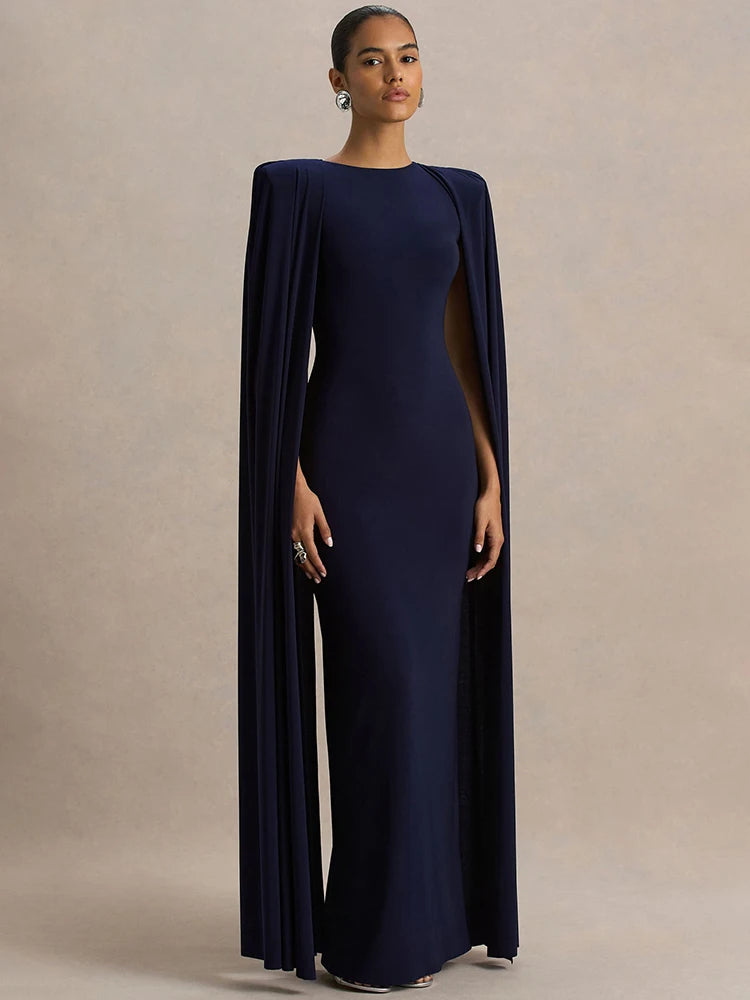 Woman wearing a navy blue evening gown with a cape on a beige background