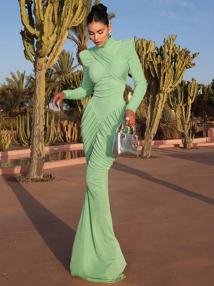 Woman in a green dress posing outdoors with cacti in the background