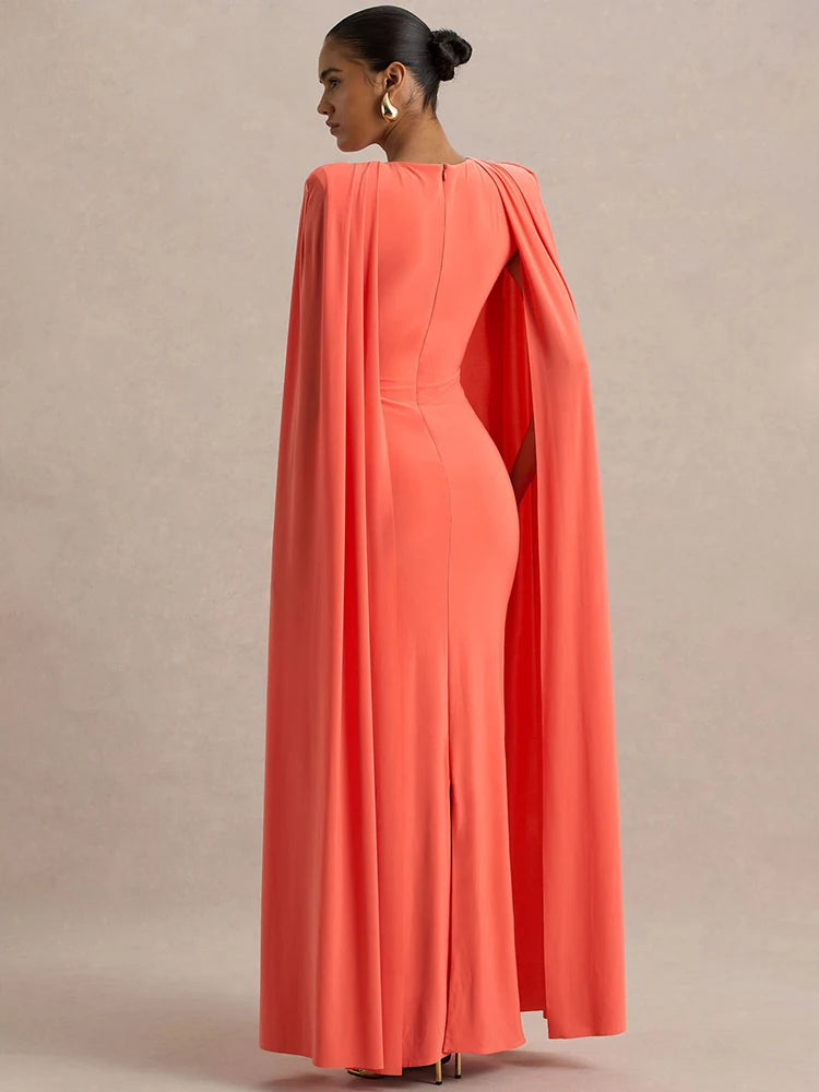 Coral evening gown with cape on a neutral background