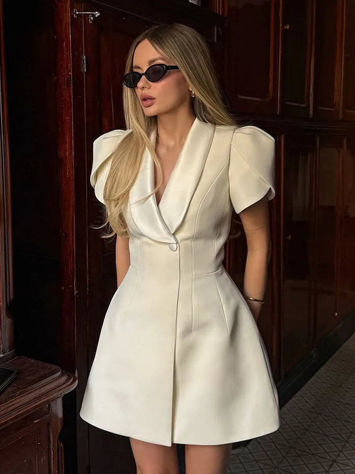 Woman wearing a white dress with puffed sleeves in an indoor setting.