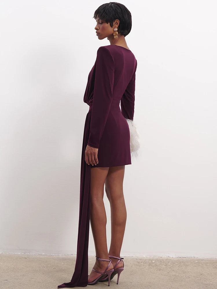 Woman wearing a burgundy dress with a long slit on a white background