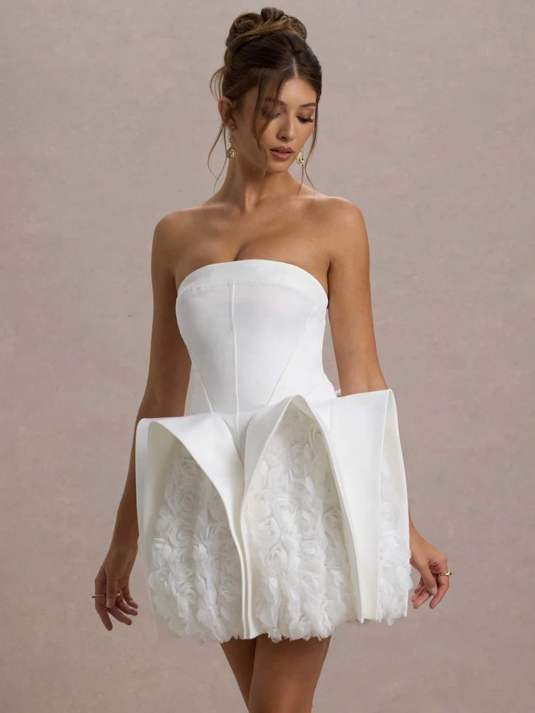 Woman wearing a strapless white dress with lace details on a plain background