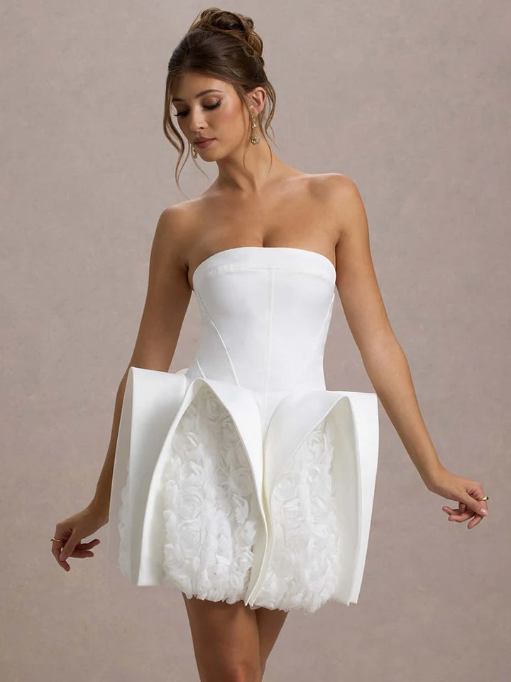 Woman wearing a strapless white dress with floral details on a beige background