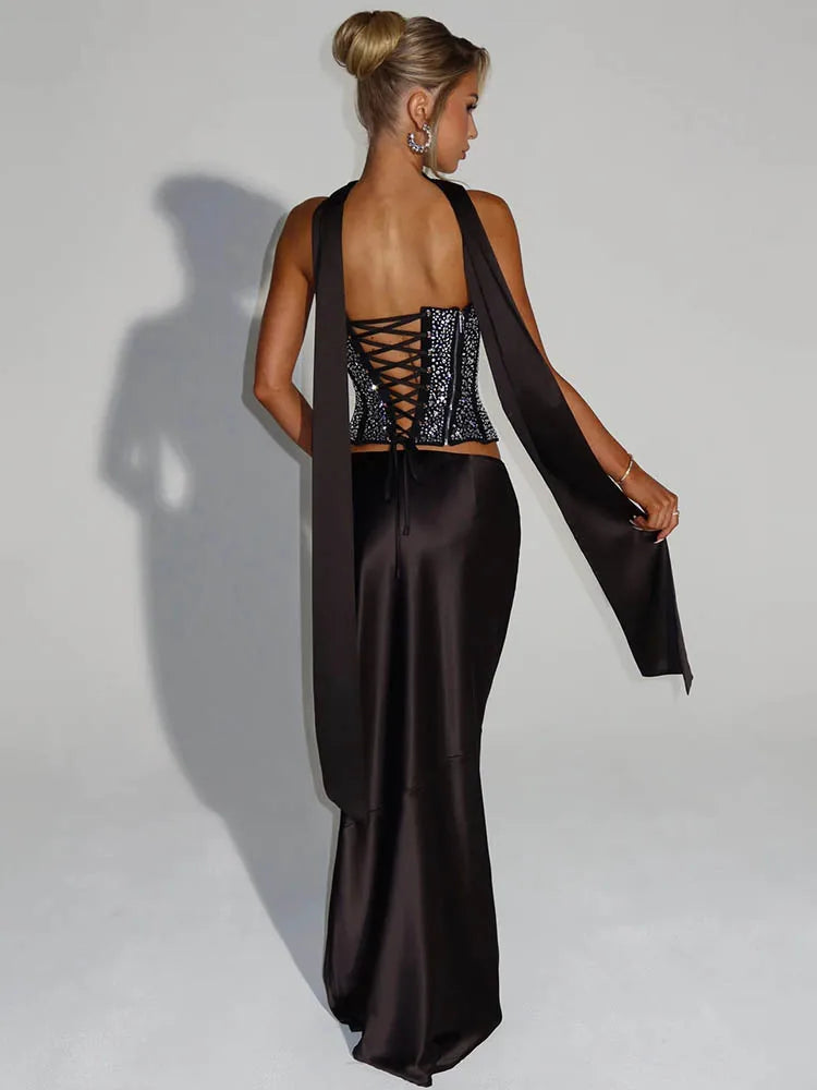 Woman wearing a black evening gown with a sheer overlay on a plain background