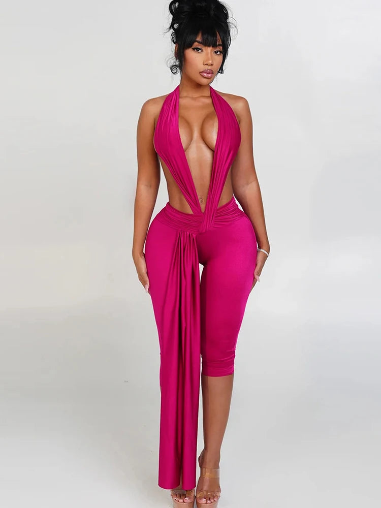 Woman wearing a bright pink jumpsuit with a plunging neckline on a white background