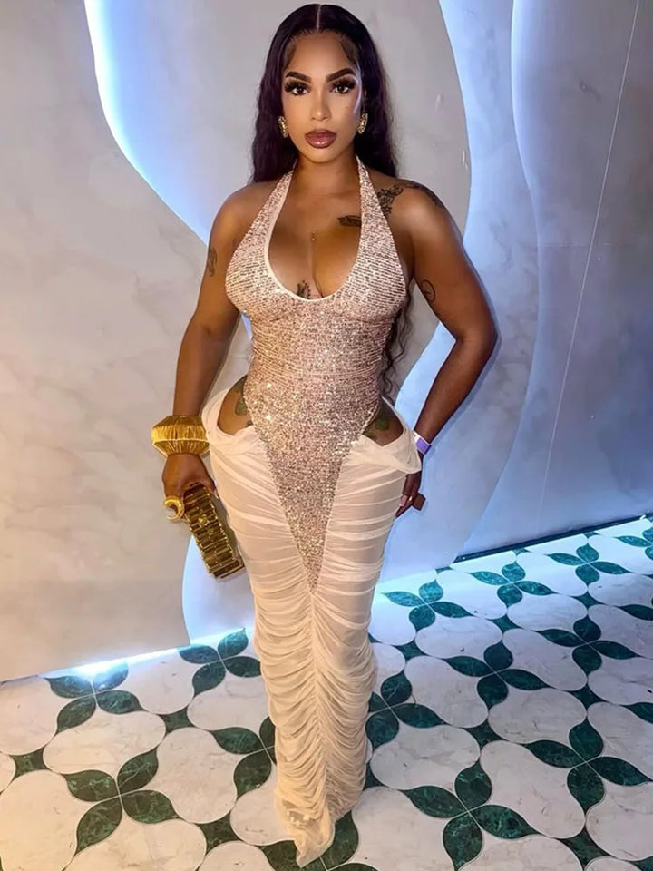 Woman in a sparkly halter top and white pants standing on a patterned floor.