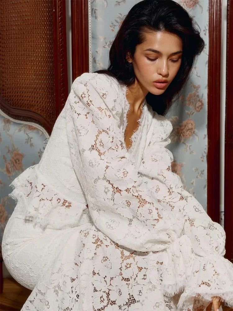 Woman wearing a white lace outfit sitting on a decorative chair.