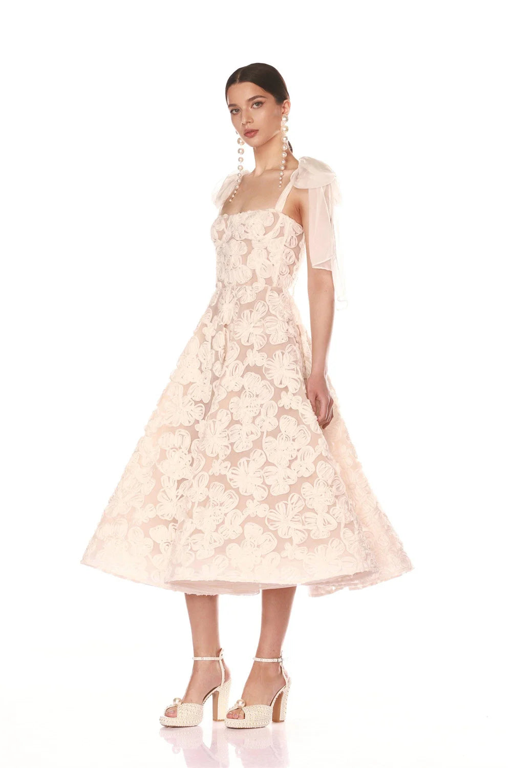 Woman wearing a light pink lace dress with sheer sleeves on a white background