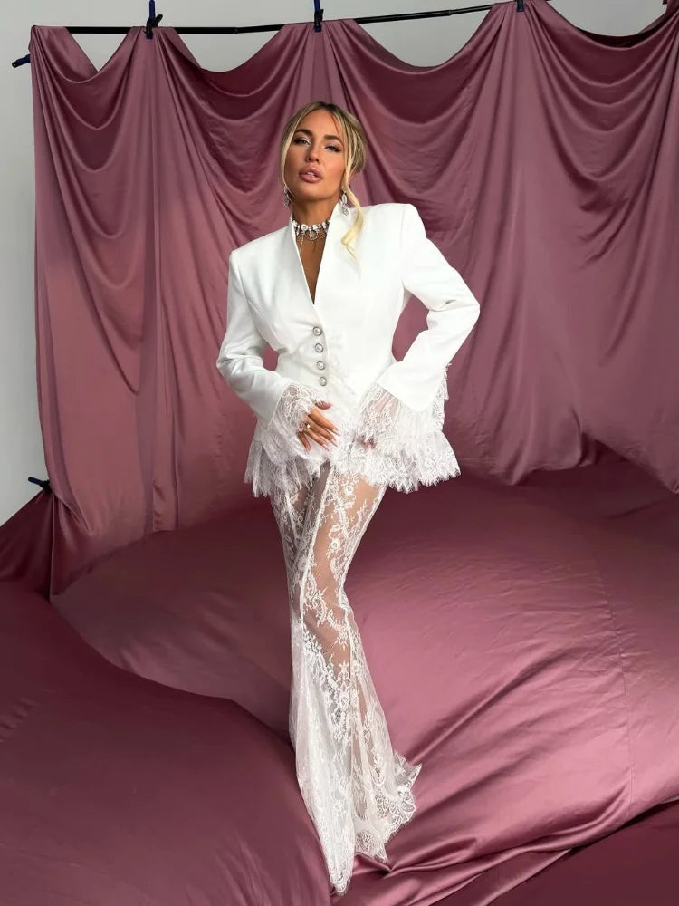 Woman in a white lace outfit standing against a draped pink curtain backdrop