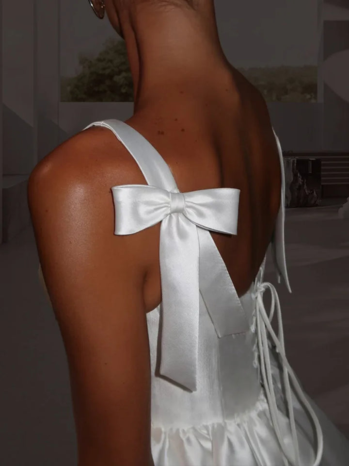 White dress with a large bow on the back, worn by a person.