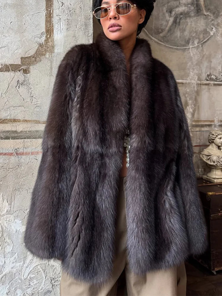 Person wearing a dark fur coat in an indoor setting with decorative elements.
