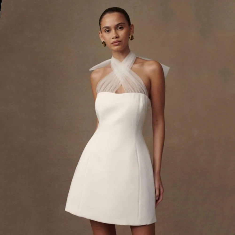 Woman wearing a white dress with a sheer neckline against a brown background