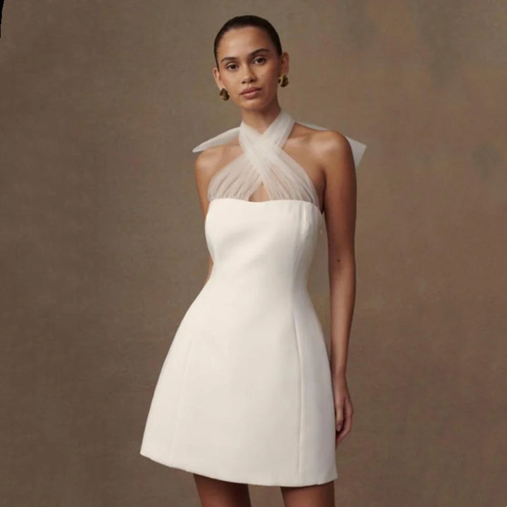 Woman wearing a white dress with a sheer neckline against a brown background