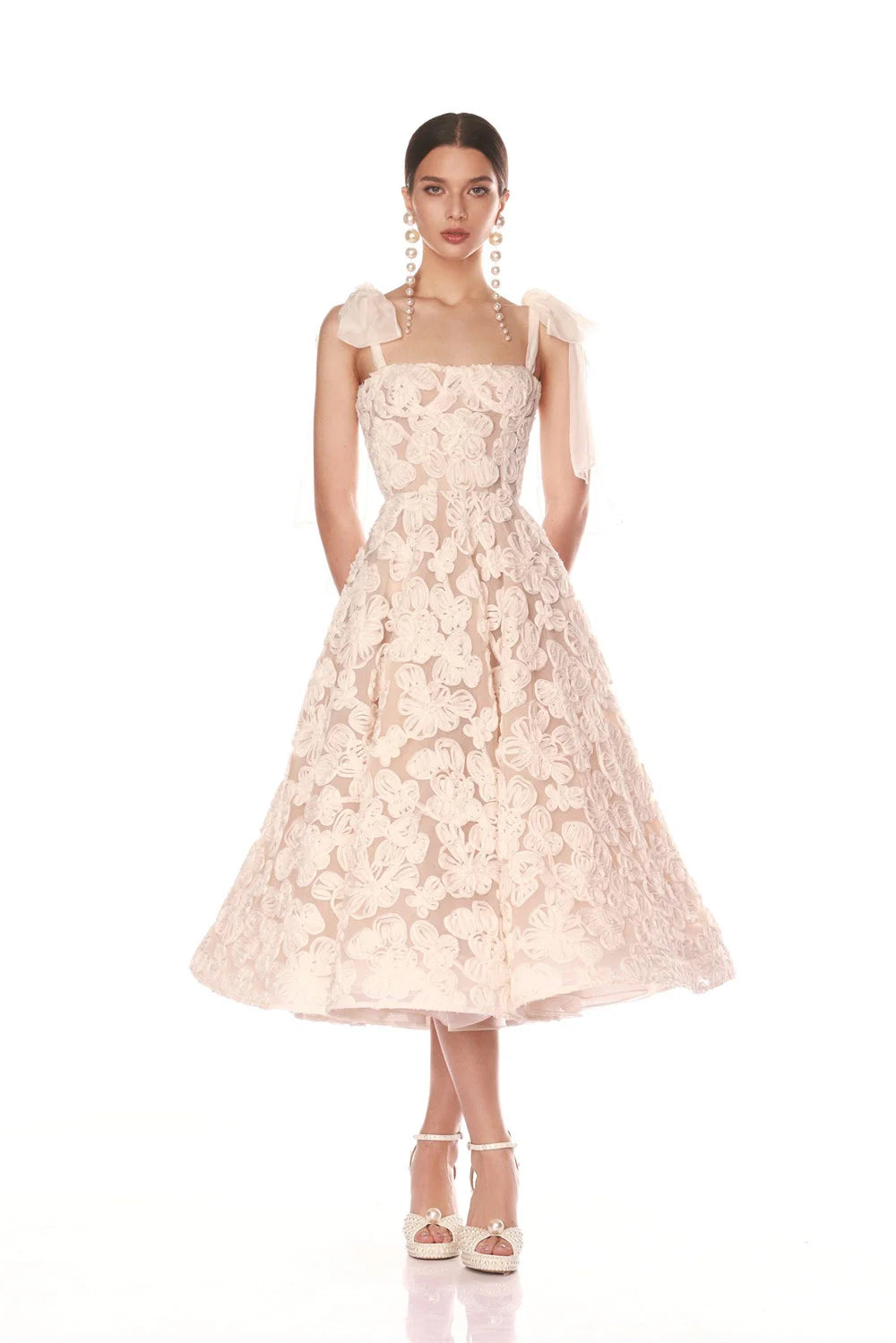 Woman wearing a light pink floral lace dress on a white background