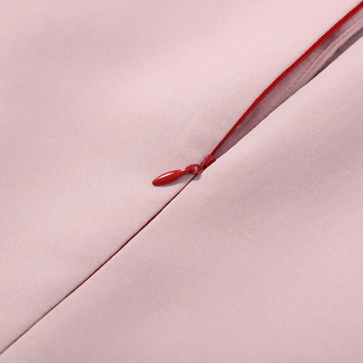 Close-up of a red zipper on a pink fabric background