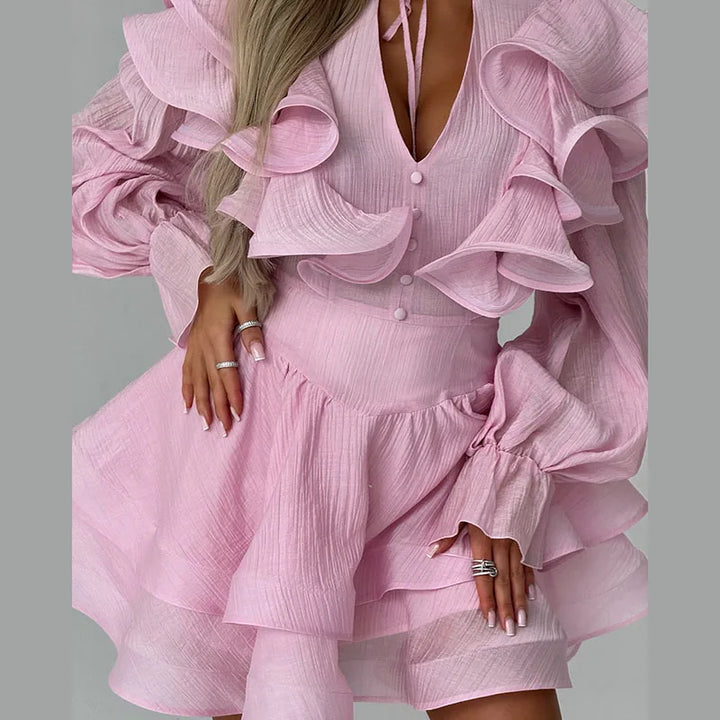 Pink ruffled dress worn by a person on a gray background