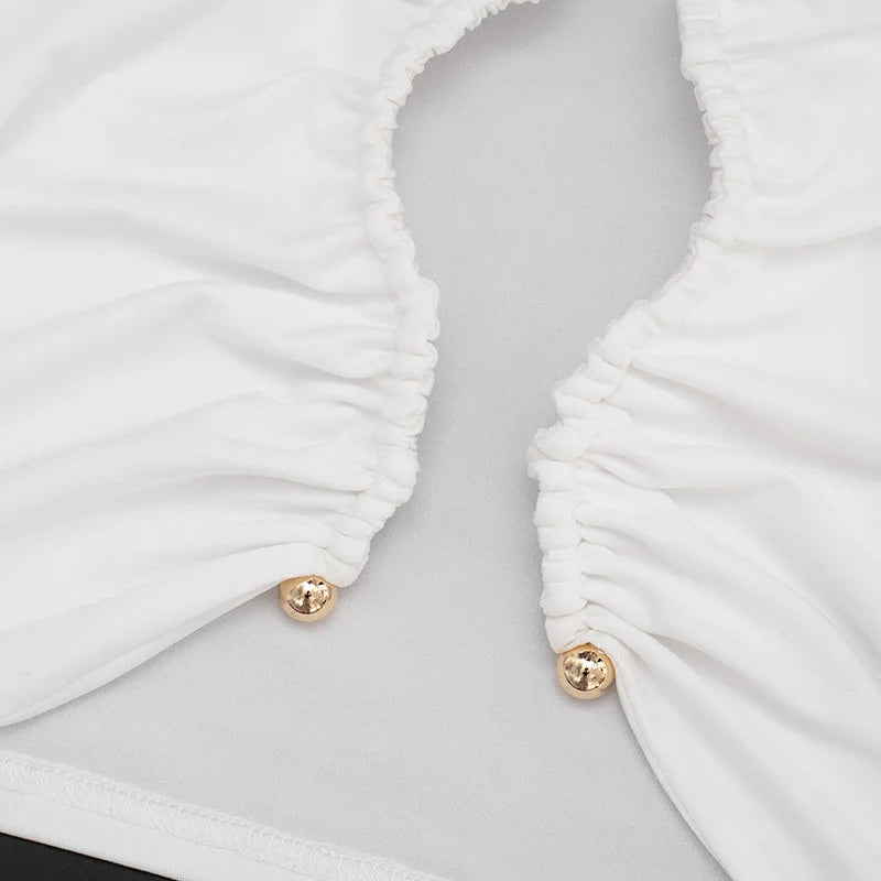 Close-up of a white ruched garment with gold buttons on a light gray background