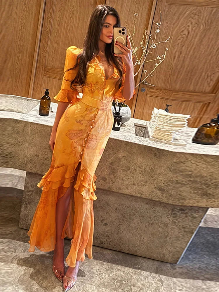 Woman in a yellow dress taking a mirror selfie in a bathroom.