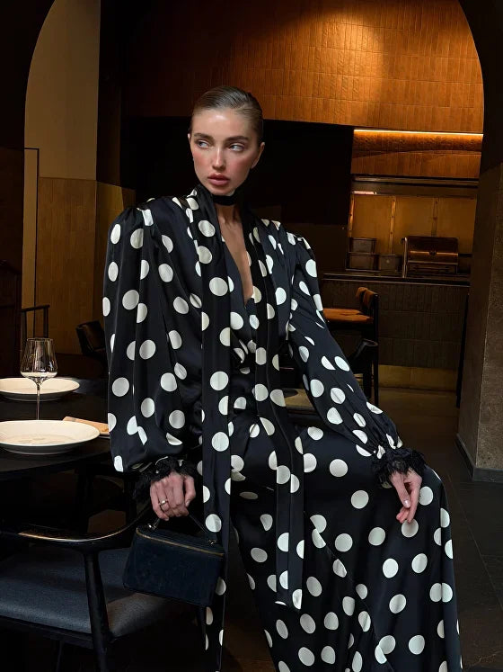 Person wearing a black polka dot coat in an indoor setting