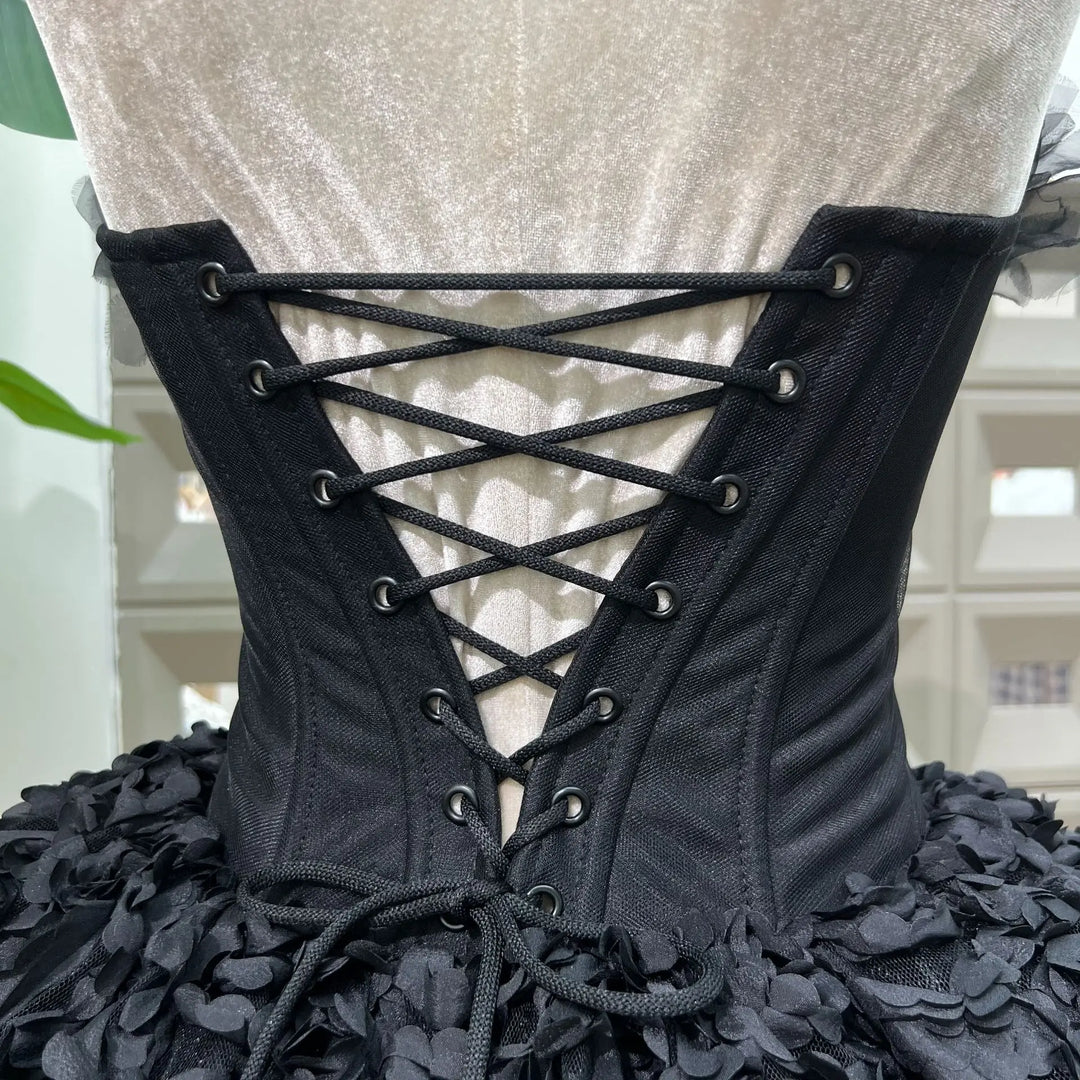 Black lace-up corset with floral details on a mannequin against a neutral background