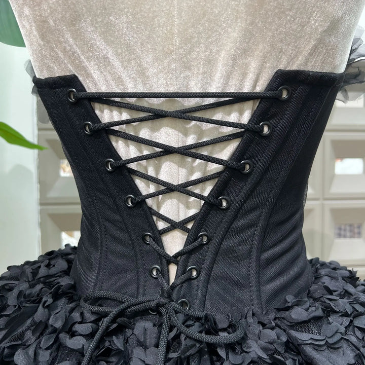 Black lace-up corset with floral details on a mannequin against a neutral background