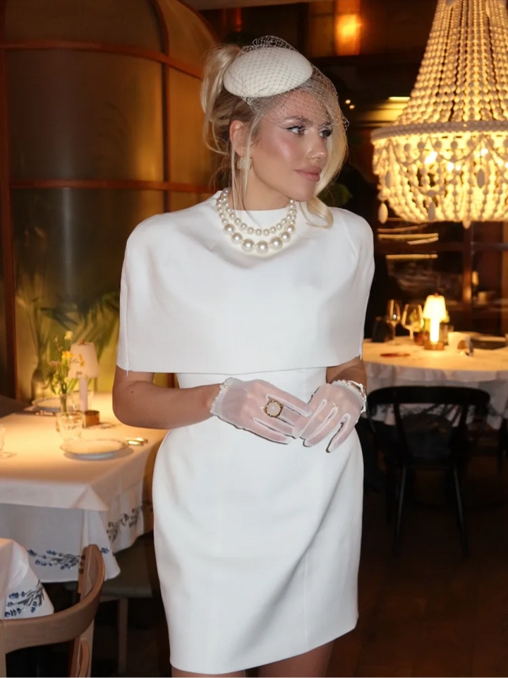 Woman wearing a white dress against a plain background