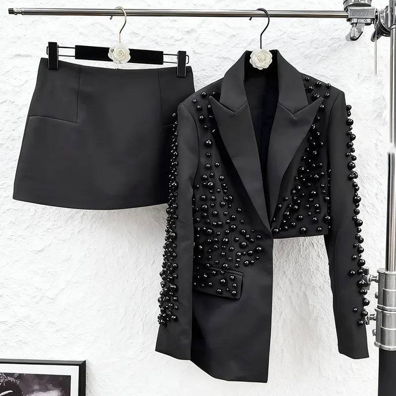 Black blazer with bead details and black skirt on a white background