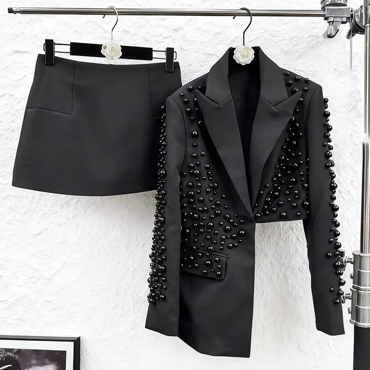 Black blazer with bead details and black skirt on a white background