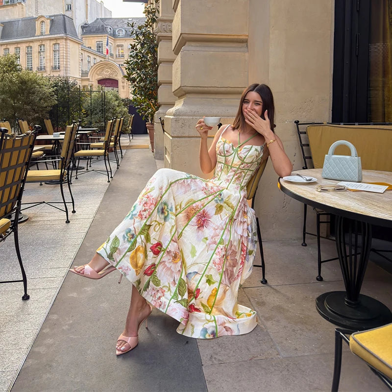 Woman in a floral dress sitting outdoors near a cafe.