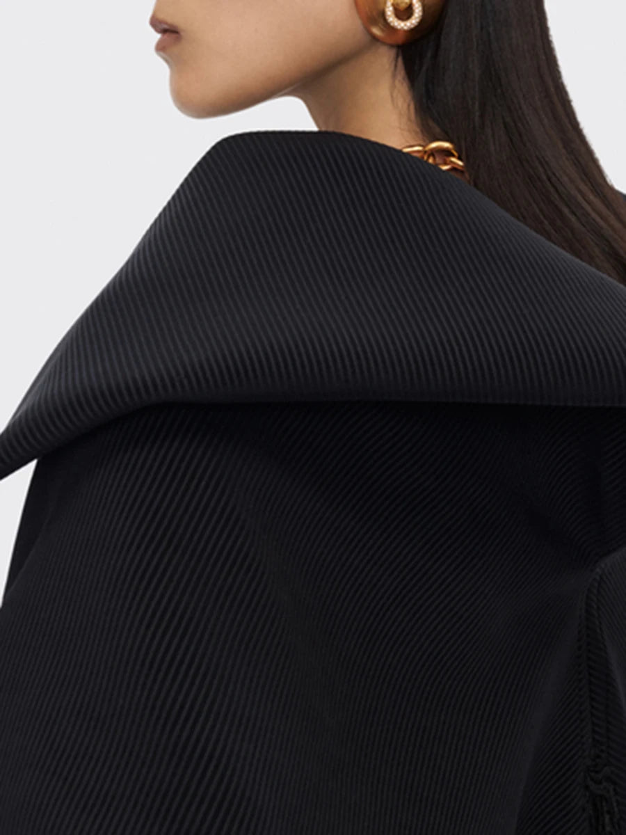Close-up of a person wearing a black ribbed sweater with a blurred background