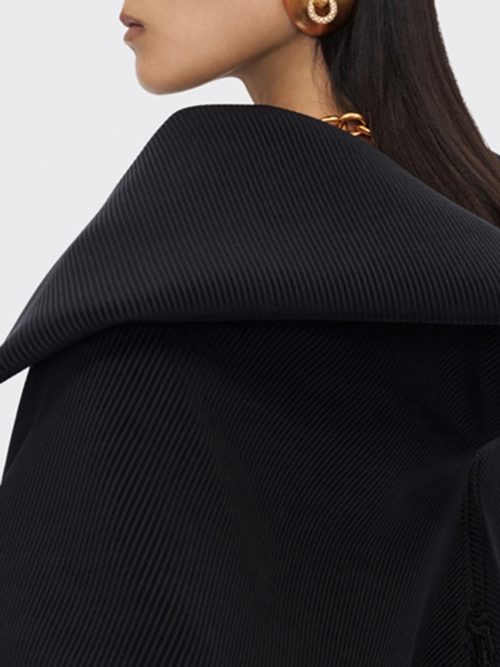 Close-up of a person wearing a black ribbed sweater with a blurred background