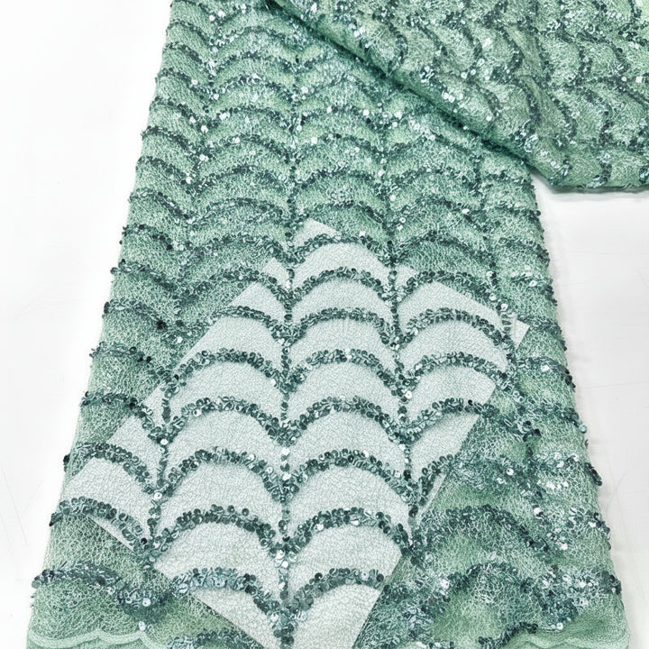 Green sequin fabric with wavy pattern on a white background