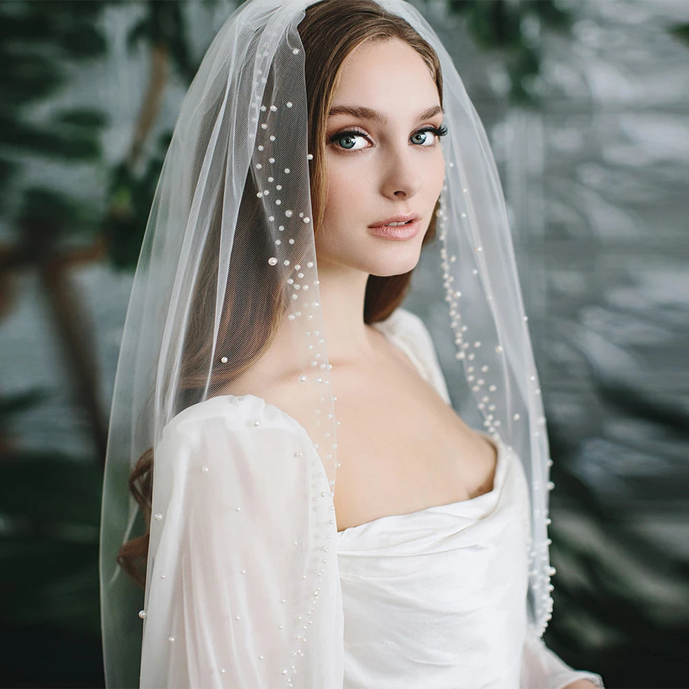 Woman wearing a white wedding dress with a veil against a blurred green background