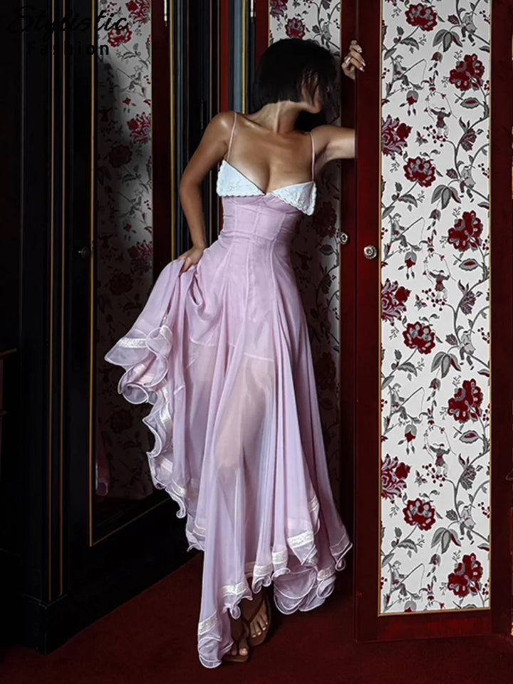 Woman in a pink dress standing in front of a floral-patterned door.