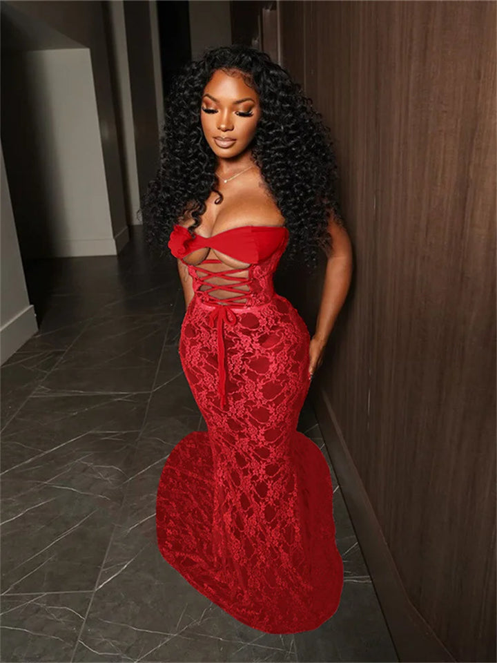 Woman wearing a red lace dress standing in a hallway.