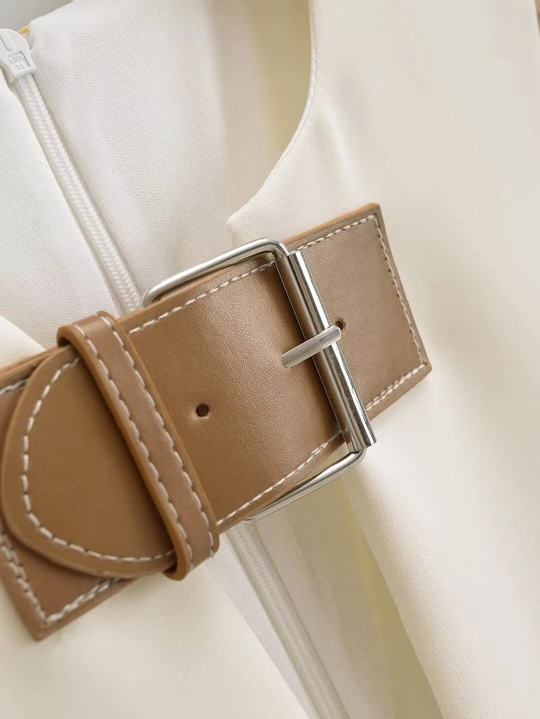 Close-up of a beige belt with a silver buckle on a light background