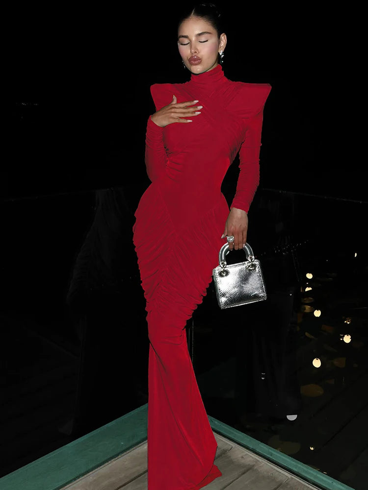 Woman in a red dress holding a silver handbag against a dark background