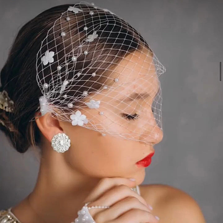 Woman wearing a decorative headpiece with flowers and pearls on a gray background