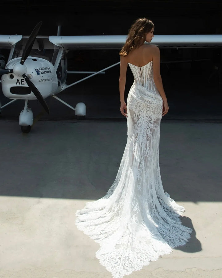Woman in a white lace dress standing in front of a small airplane