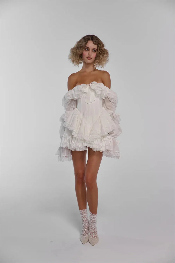 Woman wearing a white ruffled dress and high-heeled shoes on a plain background