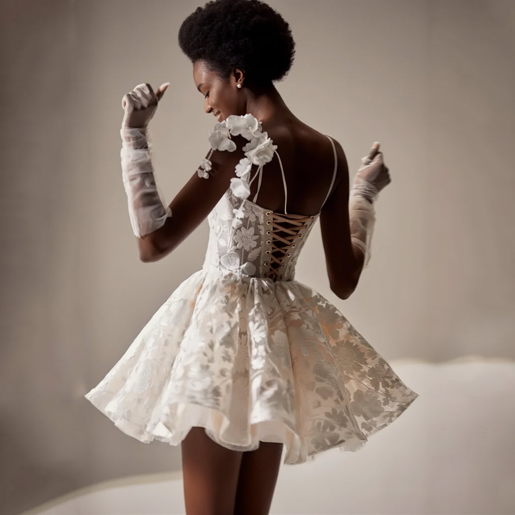 Woman wearing a white lace dress with long gloves against a neutral background