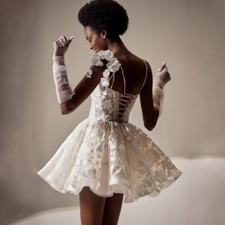 Woman wearing a white lace dress with long gloves against a neutral background