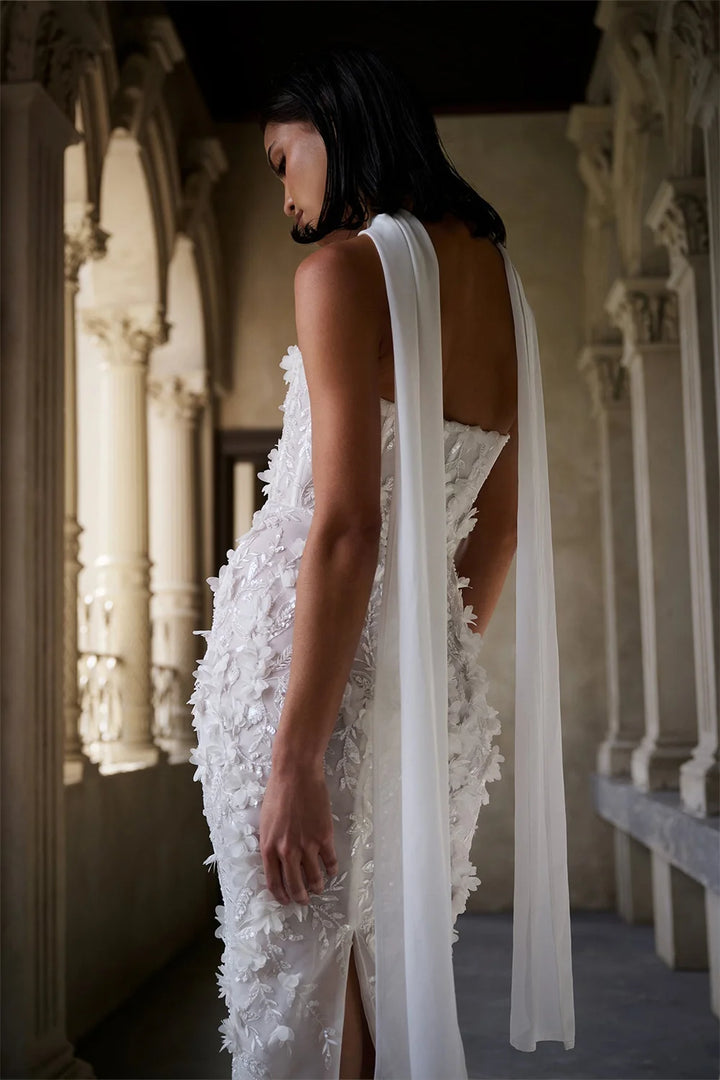 Woman in a white floral wedding dress with a long train in an elegant setting.