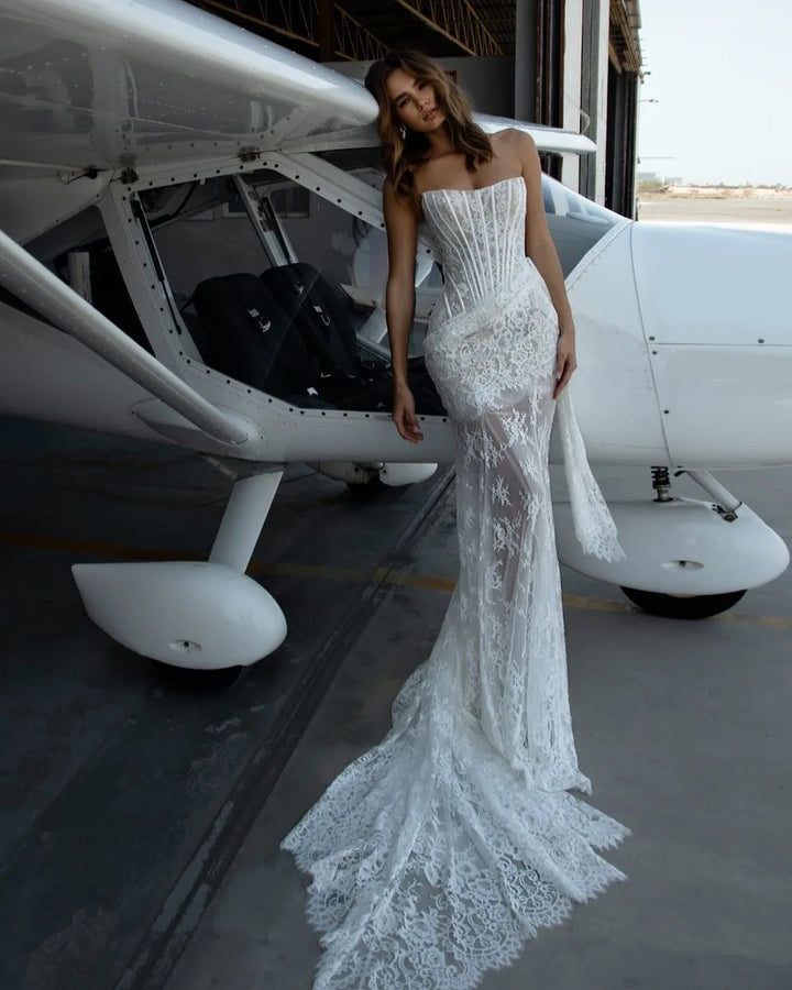 Woman in a white lace dress standing next to a small airplane