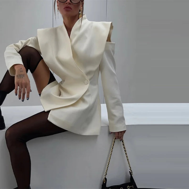 Person wearing a white outfit with a large collar, sitting against a plain background.